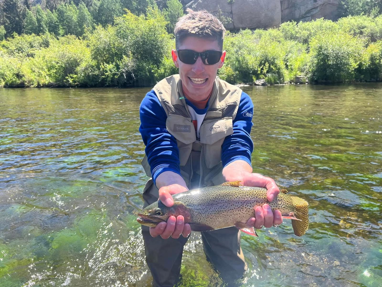 Angler holding a large trout in a granite river canyon