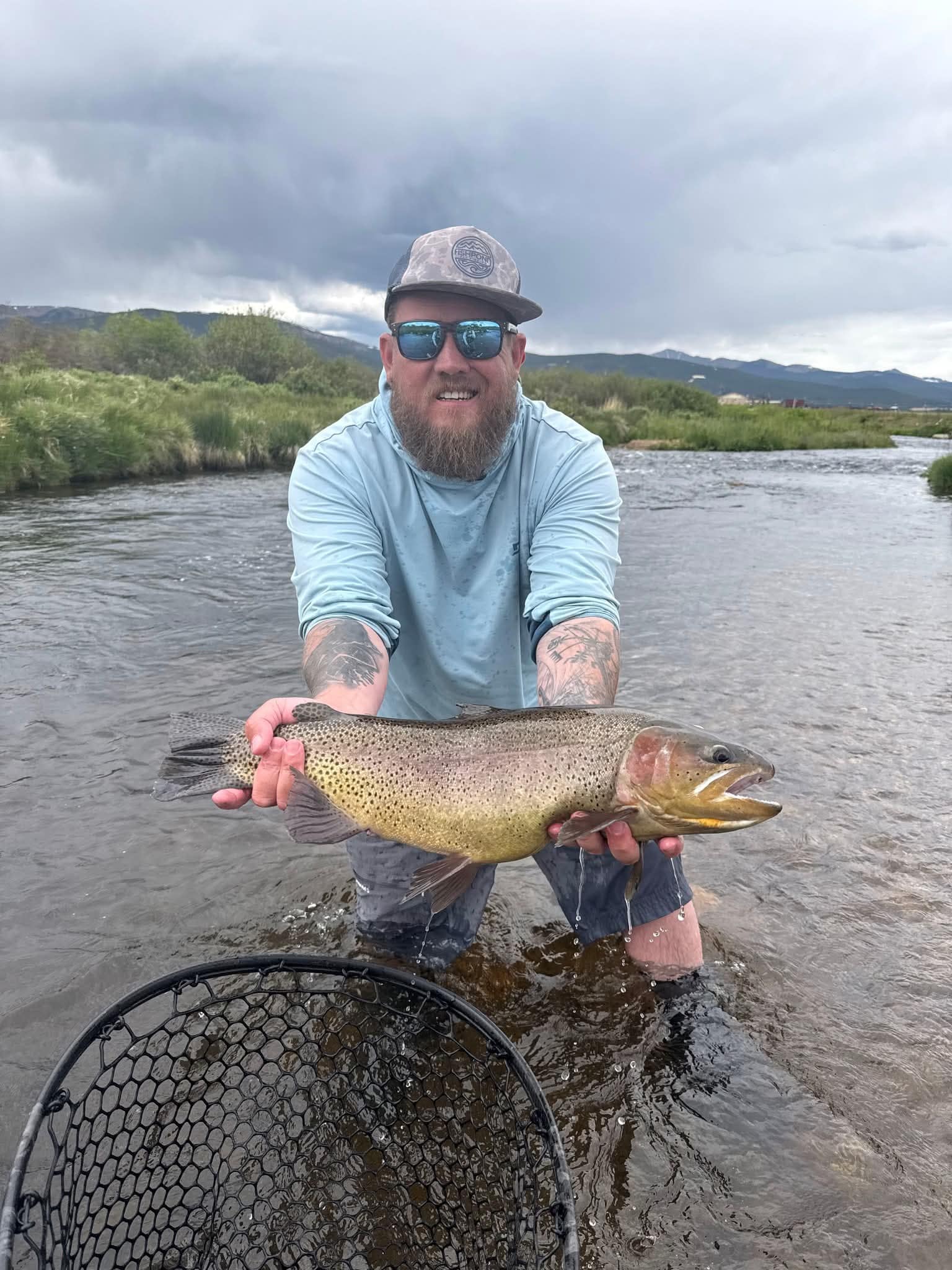 Cole Atchley on a Colorado river holding a cutthroat trout