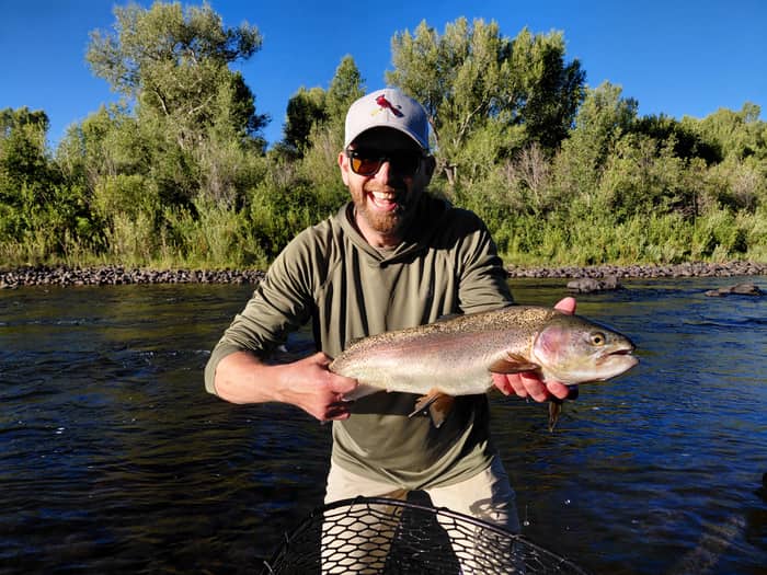Angler holding a rainbow trout streamside