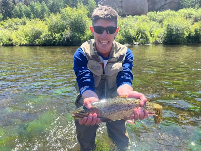 Angler holding a cutthroat trout in a granite canyon