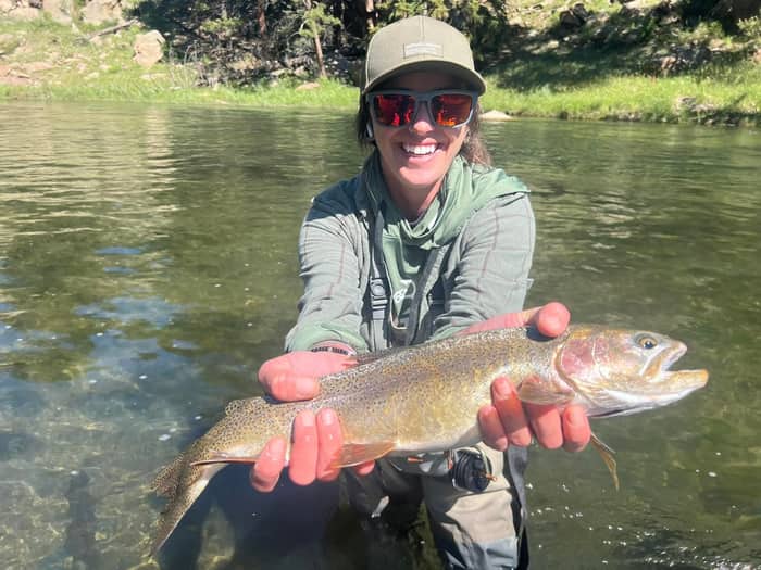 Angler holding a cutthroat trout over clear water