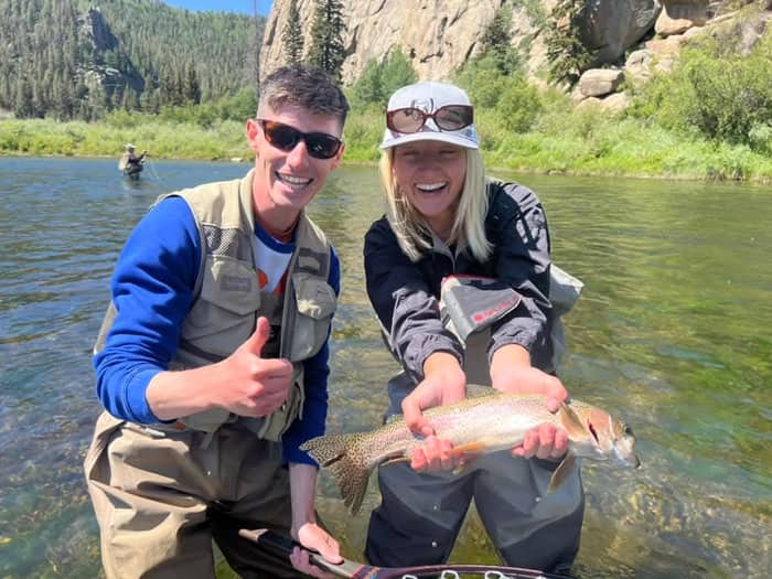 Two anglers holding a rainbow trout in a canyon river