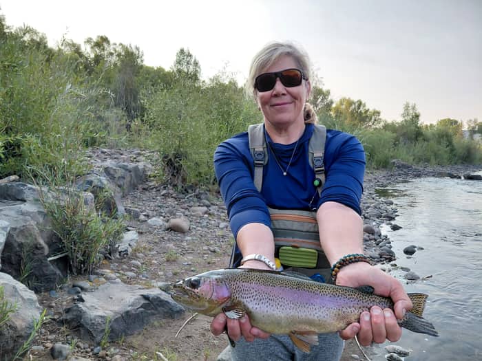 Angler holding a rainbow trout in evening light