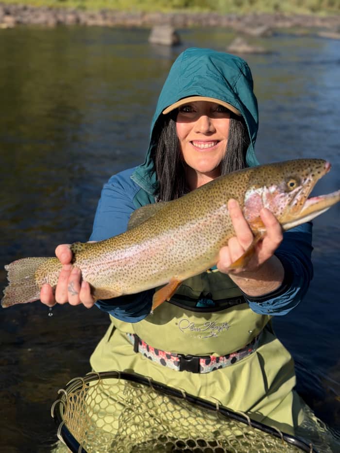 Angler holding a rainbow trout net-side on a Colorado river