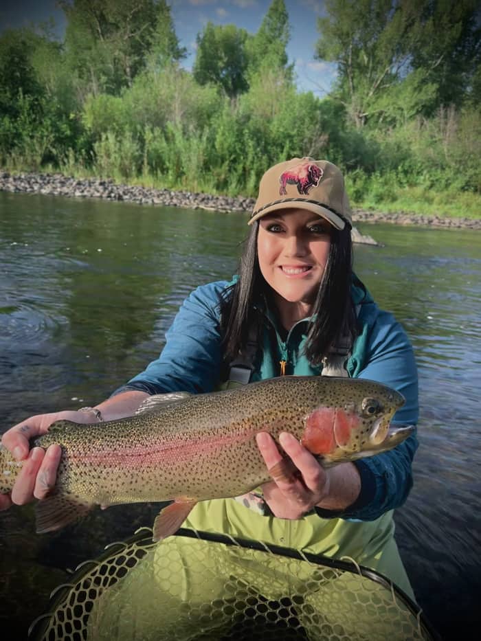 Angler holding a rainbow trout in bright sun on a Colorado river