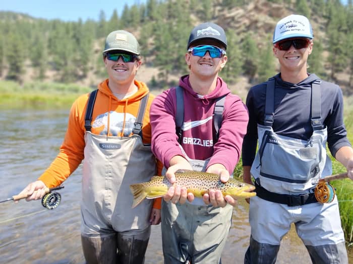 Three anglers holding a brown trout on a Colorado river