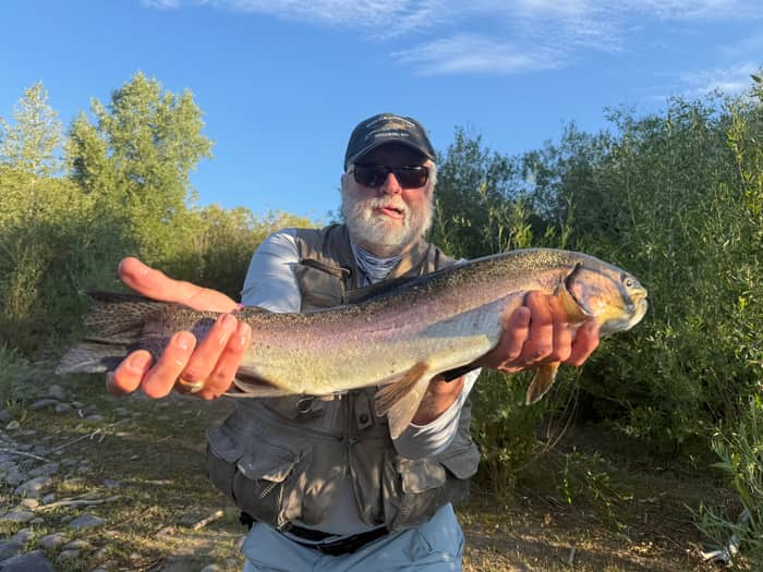 Angler cradling a trout at dusk on a Colorado river